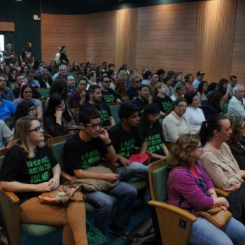 A foto mostra o auditrio lotado, com as pessoas sentadas em cadeiras, algumas j usando a camiseta da campanha.