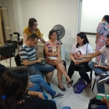 A imagem mostra uma roda de alunos do curso sentados conversando. Em p, atrs da roda, atenta ao que  dito, est Diele Pedrozo Santo.