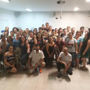 A imagem  uma foto com 40 homens e mulheres, de diferentes idades, que participaram do curso. Eles esto lado a lado, sendo a maioria em p e alguns agachados, sorrindo para a foto, no auditrio do IPC.