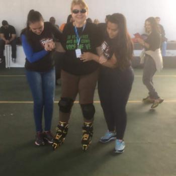 Uma mulher est em p sobre patins, olha pra frente e sorri. Ela tem cabelos claros curtos, usa culos pretos, camiseta preta da campanha Bengala Verde, do IPC, com os dizeres 